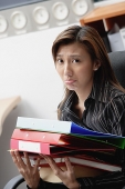 Female executive carrying folders and binders, frowning - Asia Images Group