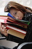 Female executive leaning on stack of binders - Asia Images Group