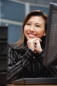 Female executive at desk, hands clasped, smiling - Asia Images Group