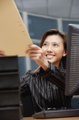 Female executive handing folder to someone in front of her - Asia Images Group
