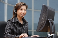 Businesswoman with hands free device, using computer - Asia Images Group