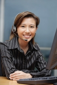 Businesswoman with hands free device, arms crossed - Asia Images Group