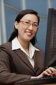 Female executive with computer, smiling at camera - Asia Images Group