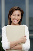 Female executive hugging folders, smiling at camera - Asia Images Group
