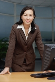 Businesswoman leaning on table, portrait - Asia Images Group