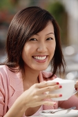 Woman holding coffee cup, smiling at camera - Asia Images Group