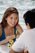 Couple sitting at outdoor cafe, woman opening gift box, smiling at man - Asia Images Group