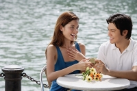 Couple sitting at outdoor cafe, man giving woman a gift - Asia Images Group