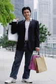 Man standing with shopping bags, smiling at camera - Asia Images Group