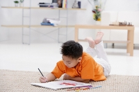 Boy lying on floor with sketch pad - Asia Images Group