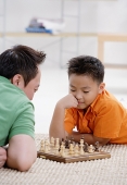 Father and son at home, playing chess - Asia Images Group