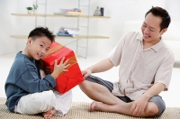 Father and son at home, boy holding big gift box - Asia Images Group