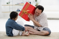 Father and son at home, father holding big gift box - Asia Images Group