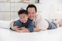 Father and son lying on floor, embracing, portrait - Asia Images Group