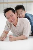 Father lying on floor, son lying on top of him, portrait - Asia Images Group