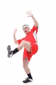 Man in soccer uniform, standing on one leg, shocked expression - Asia Images Group