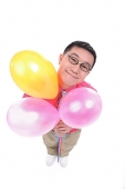 Man holding balloons, smiling at camera - Asia Images Group