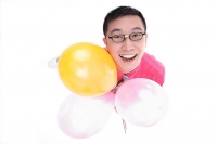 Man holding balloons, looking up at camera - Asia Images Group
