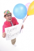 Man with party hat, holding balloons and a birthday greeting sign - Asia Images Group