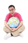Man sitting on floor, hugging globe - Asia Images Group