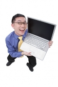 Businessman with open laptop, looking at camera, smiling - Asia Images Group