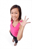 Young woman making OK sign, smiling up at camera - Asia Images Group