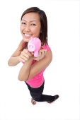 Young woman holding piggy bank, smiling up at camera - Asia Images Group