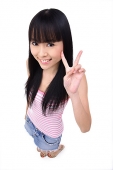 Young woman making peace sign, smiling up at camera - Asia Images Group