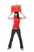 Young woman balancing big red gift box on her head - Asia Images Group