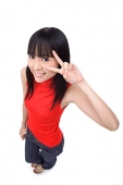 Young woman making peace sign, smiling up at camera - Asia Images Group