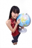 Young woman holding and pointing at globe - Asia Images Group