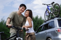 Man on a bike, woman standing next to him, looking at camera - Asia Images Group