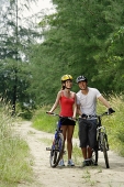 Couple standing with bicycles, smiling at camera - Asia Images Group