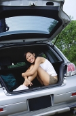 Woman sitting in boot of car, smiling at camera - Asia Images Group