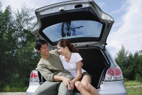 Couple sitting in boot of car - Asia Images Group