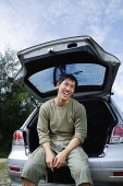 Man sitting in boot of car - Asia Images Group