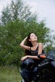 Young woman on motorcycle, looking up - Asia Images Group