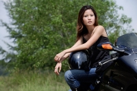 Young woman on motorcycle, looking at camera - Asia Images Group