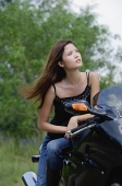 Young woman on motorcycle, looking away - Asia Images Group