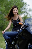 Young woman on motorcycle, smiling at camera - Asia Images Group