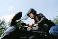Young woman riding motorbike, low angle view - Asia Images Group