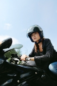 Young woman riding motorbike, low angle view - Asia Images Group