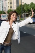 Woman standing by road, flagging a cab - Asia Images Group