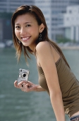 Woman holding digital camera, smiling at camera - Asia Images Group