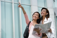 Two women with map, looking up - Asia Images Group