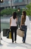 Two women walking, carrying shopping bags, rear view - Asia Images Group