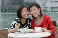 Two women at sidewalk cafe having lunch, smiling at camera - Asia Images Group