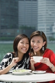 Two women having lunch, smiling at camera - Asia Images Group