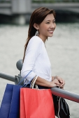 Woman with shopping bags, standing by railing - Asia Images Group