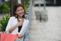 Woman carrying shopping bags, holding mobile phone, smiling - Asia Images Group